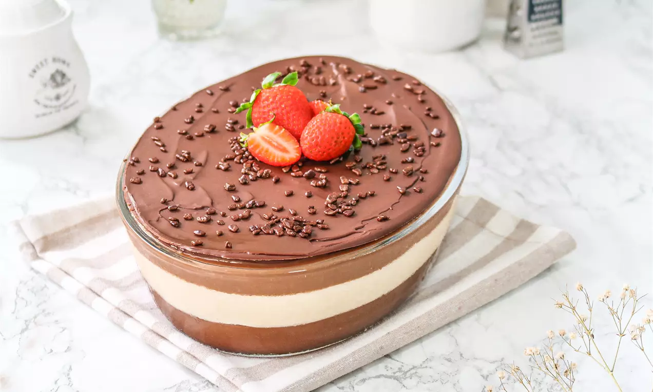 Ovo de Páscoa trufado na travessa com ganache brilhante, raspas de chocolate, confeitos coloridos e morangos fatiados ao lado