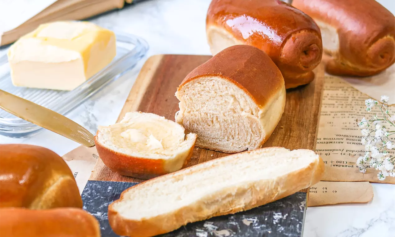 Pão de Airfryer dourado e fofinho, fatias com miolo aerado, manteiga derretida sobre tábua de madeira e guardanapo listrado