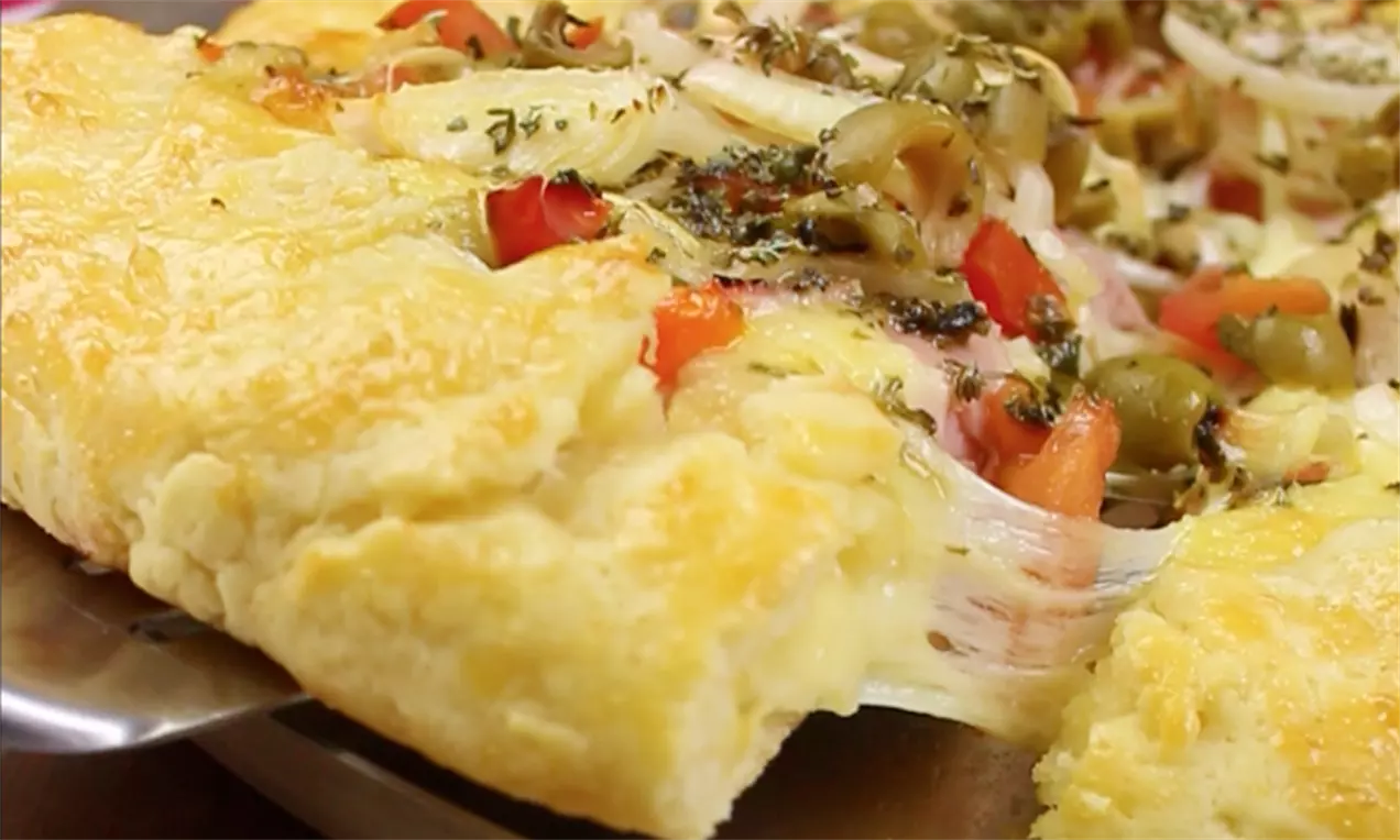 Galette com borda dourada e crocante, recheada com vegetais coloridos, queijo derretido e ervas sobre uma base rústica feita à mão